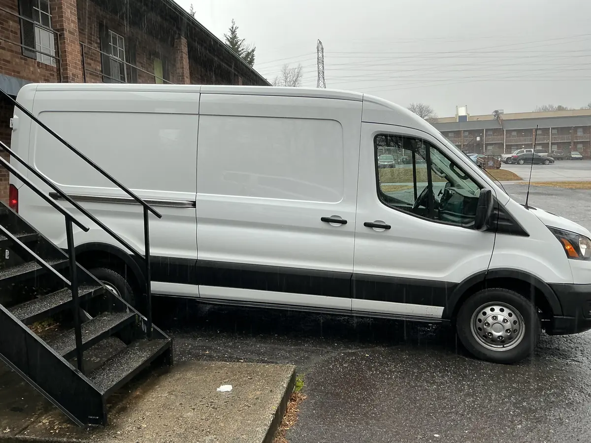 The Sprinter van parked beside a loading stair, passenger side.